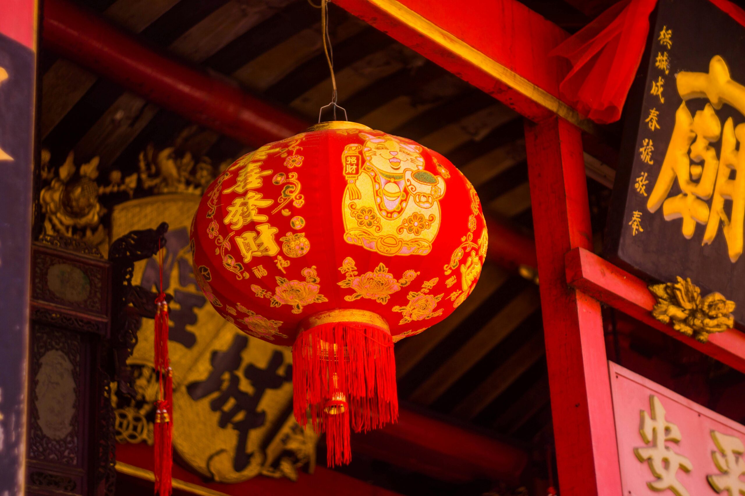 Red Chinese lantern with traditional symbols in an ornate temple setting, symbolizing culture and spirituality.